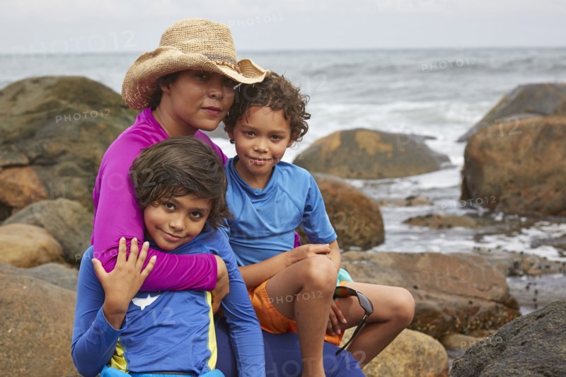 Mother and children hugging on rocky beach