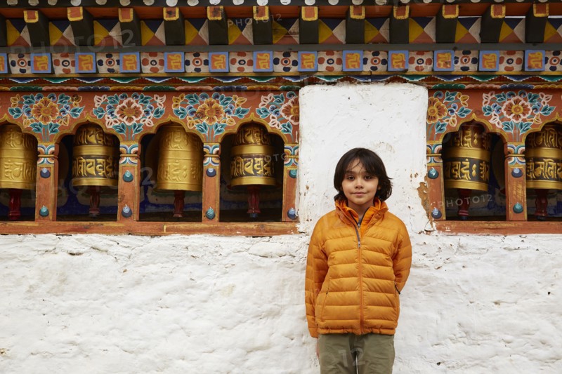 Mixed Race boy standing near prayer wheels