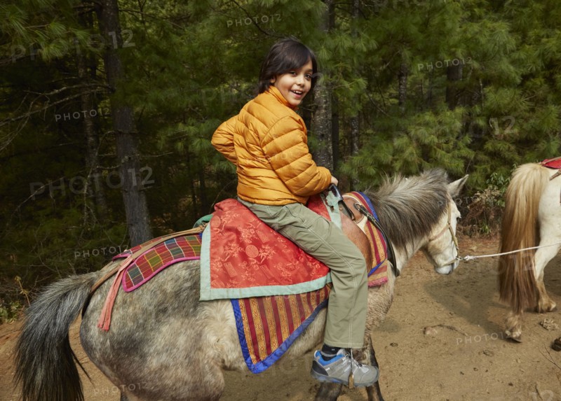 Mixed Race boy riding horse