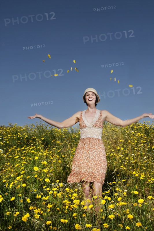 Caucasian woman throwing wildflowers in field