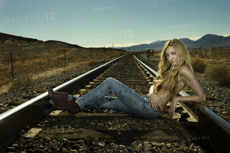 Caucasian woman laying on railroad tracks