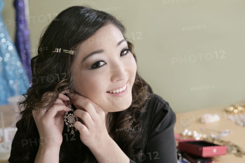 Mixed race woman putting on earrings