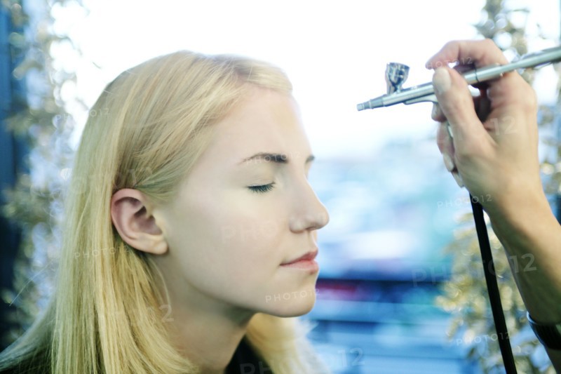 Woman having makeup spray painted on her face