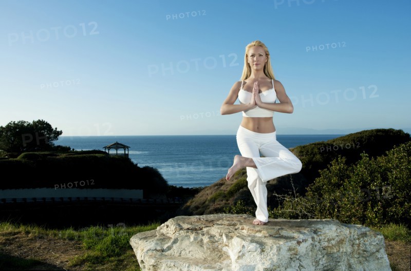 Caucasian woman practicing yoga near ocean