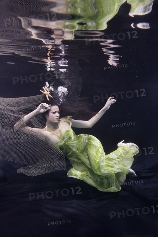 Mixed race woman in dress swimming under water