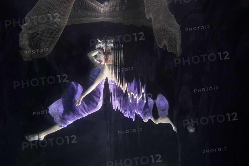 Caucasian woman in dress swimming under water