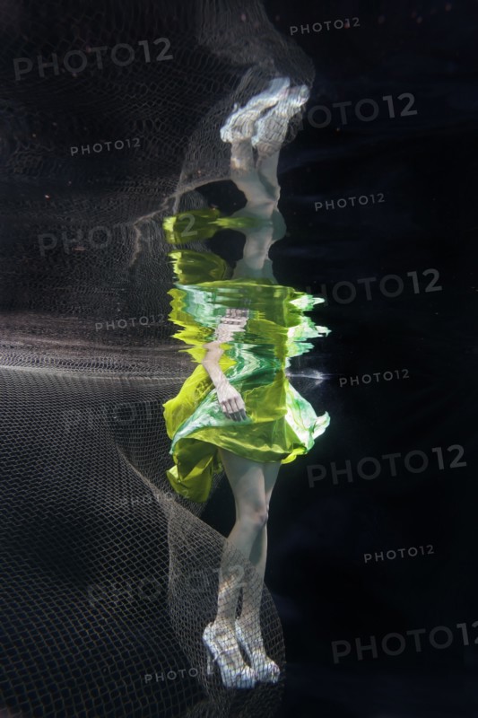 Caucasian woman in dress swimming under water
