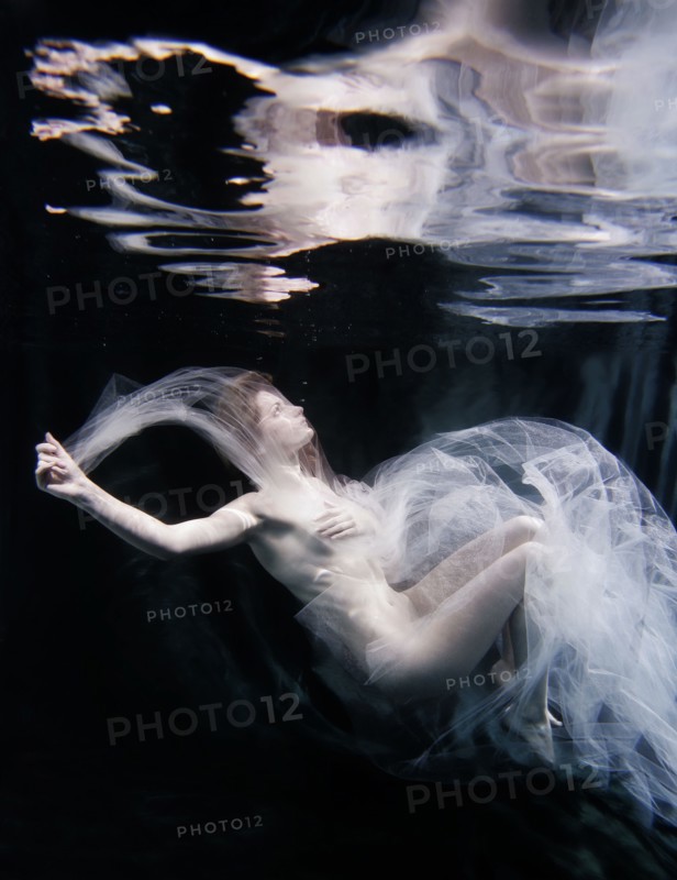 Caucasian woman in scarf swimming under water