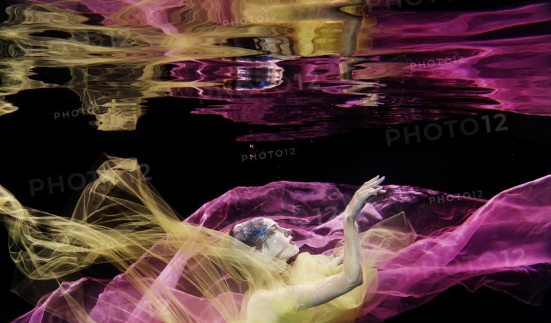 Caucasian woman in scarf swimming under water
