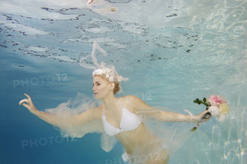Caucasian bride in bikini swimming under water