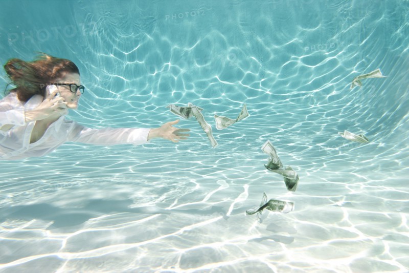 Caucasian businesswoman reaching for money underwater