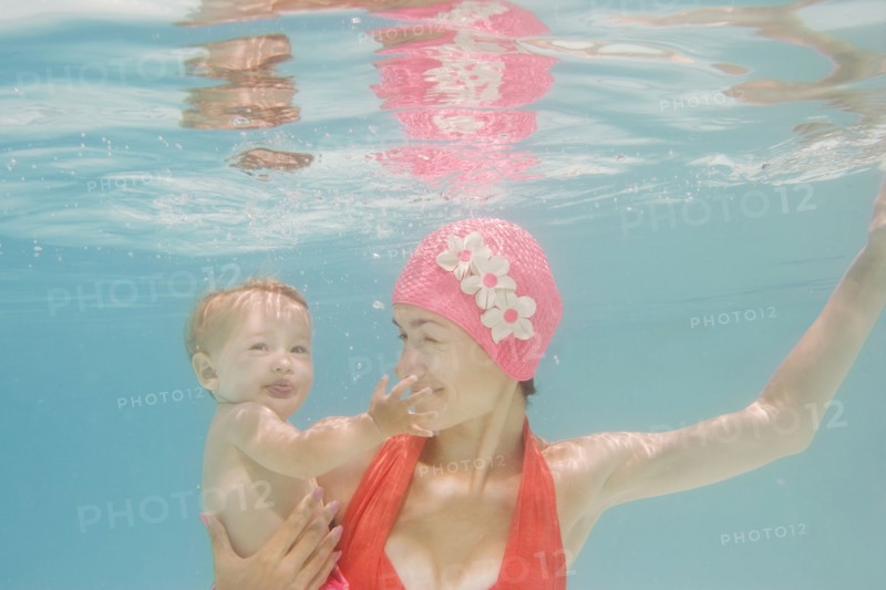 Caucasian mother holding baby underwater