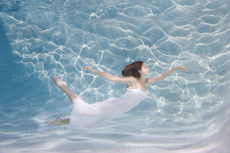 Underwater view of Caucasian woman in dress swimming in pool