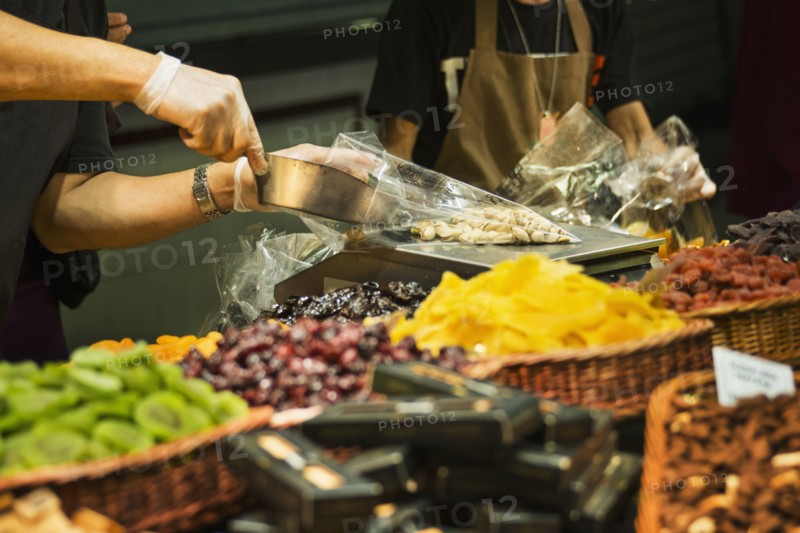 Worker scooping nuts into plastic bag at market