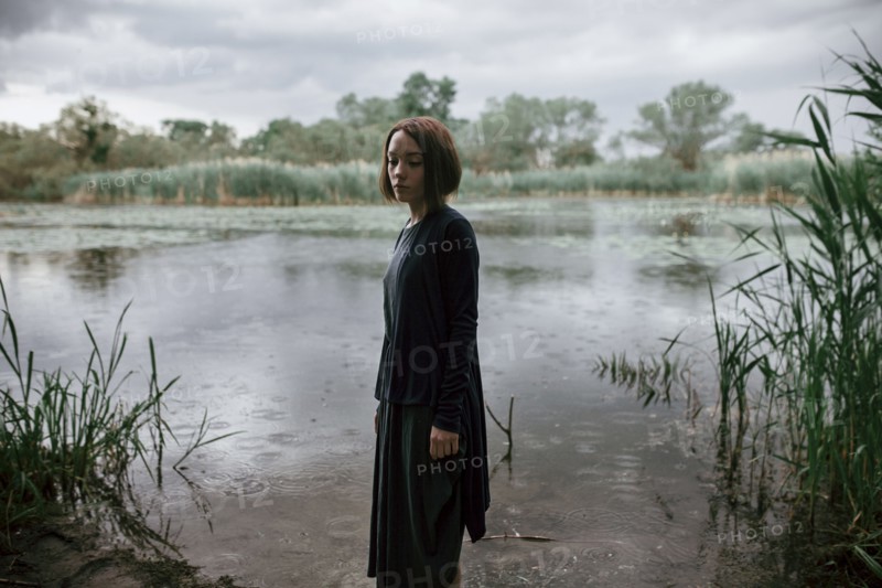 Caucasian woman standing near river in rain