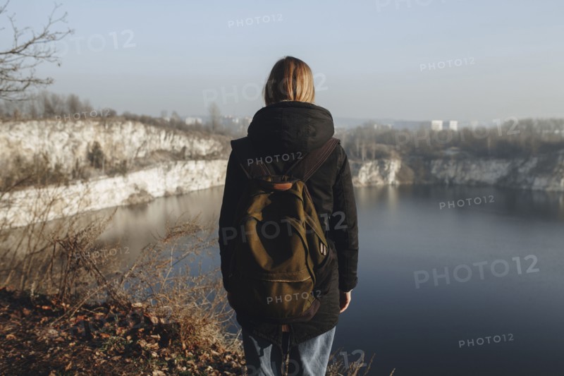 Caucasian woman standing at the edge of reservoir wearing backpack
