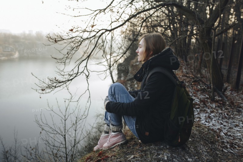 Caucasian woman sitting at the edge of reservoir wearing backpack