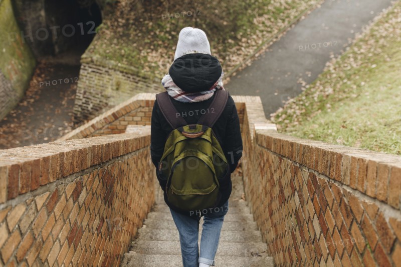 Caucasian woman carrying backpack descending staircase outdoors