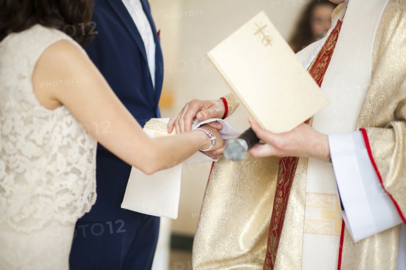 Priest and couple joining hands in wedding