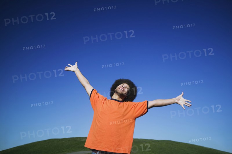 African man with arms raised under blue sky