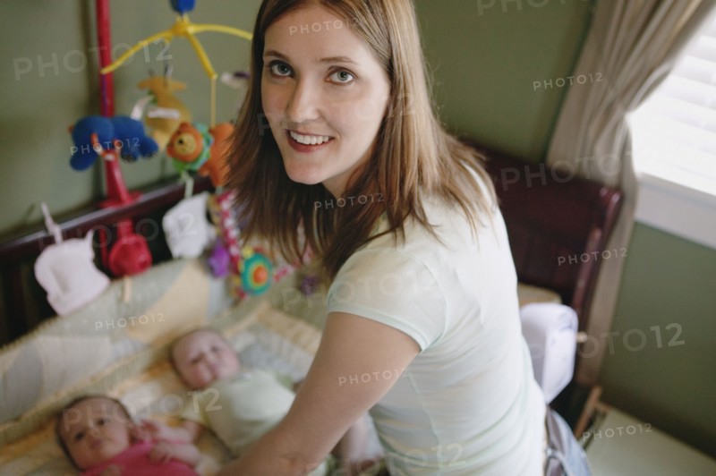 Portrait of mother and twin babies in crib