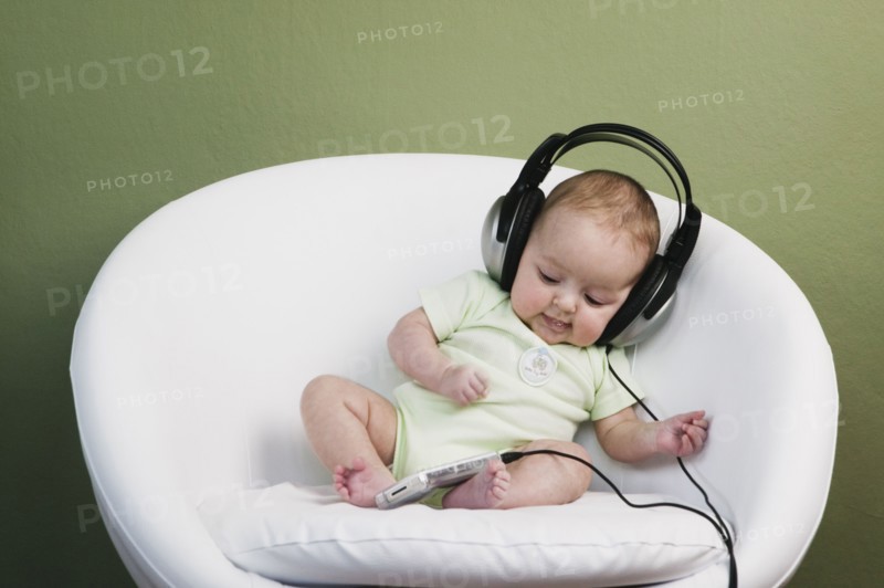 Baby in chair wearing adult headphones