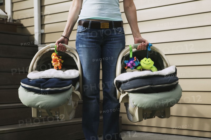 Woman carrying two baby car seats