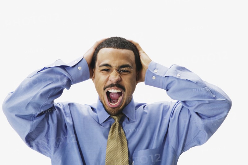 African businessman yelling with hands on head