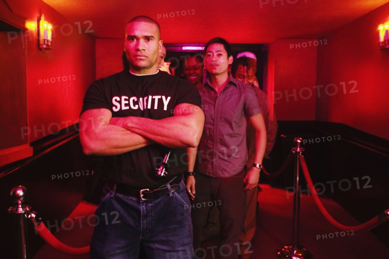 African male bouncer with arms crossed in front of people