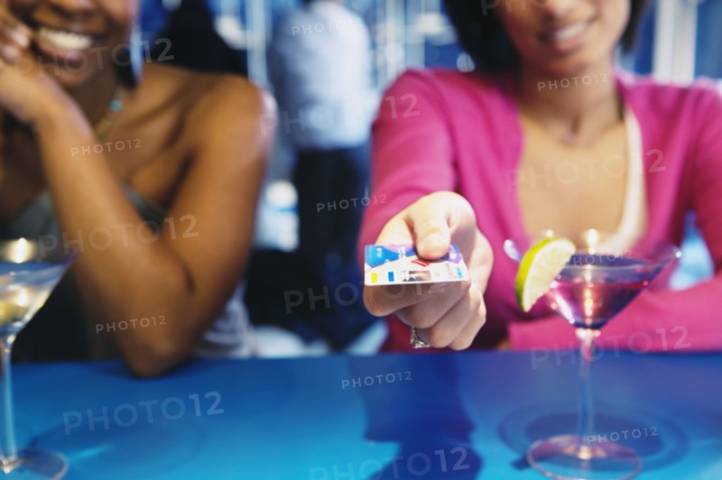 African woman handing credit card over bar