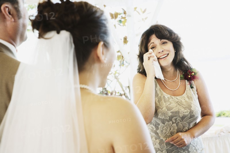 Crying woman watching bride walk down aisle