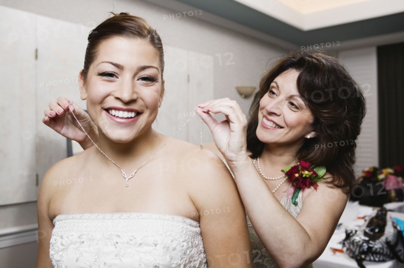 Bride's mother putting necklace on daughter