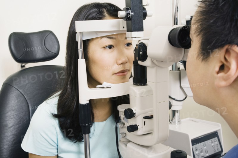 Asian male optometrist examining patient