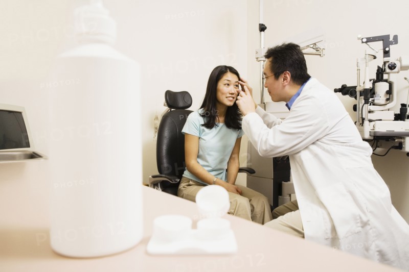 Asian male optometrist examining patient
