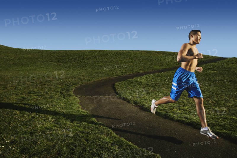 Bare chested Asian man jogging in park