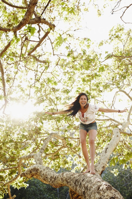 Hispanic woman standing on tree branch