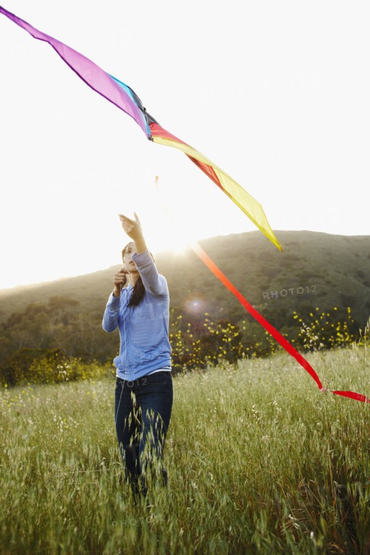 Asian woman flying kite in field
