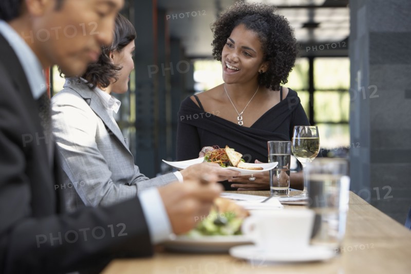 African waitress bringing food to businesswoman