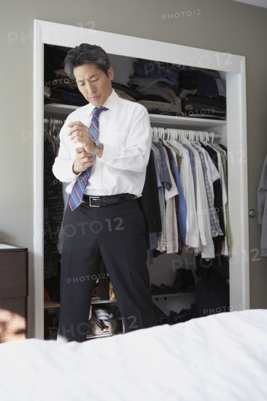 Asian businessman putting on watch