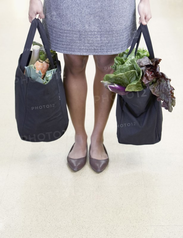 African woman holding reusable grocery bags