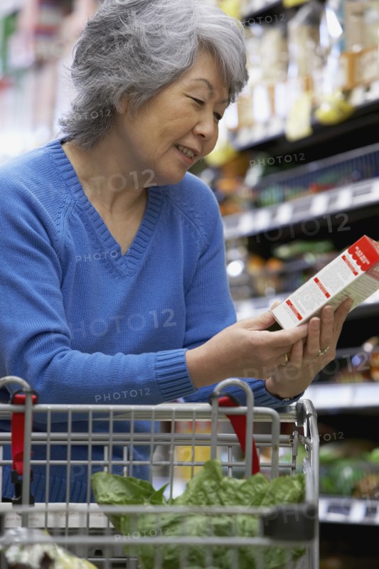 Senior Asian woman reading label at grocery store