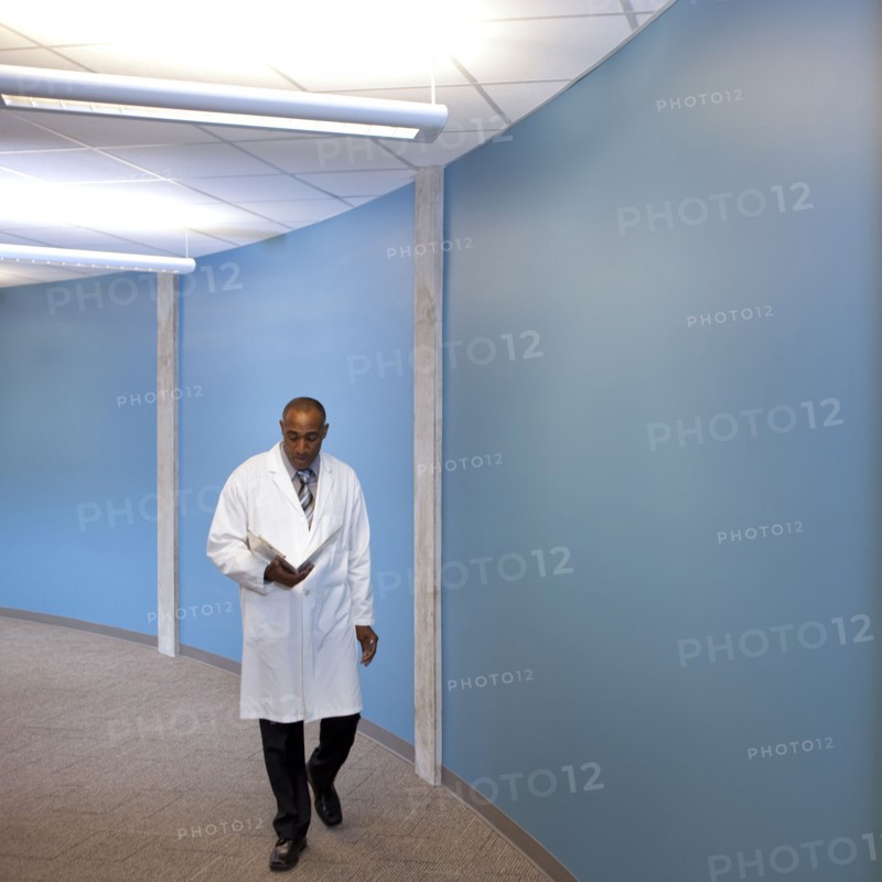 Mixed race doctor walking in hospital with medical chart