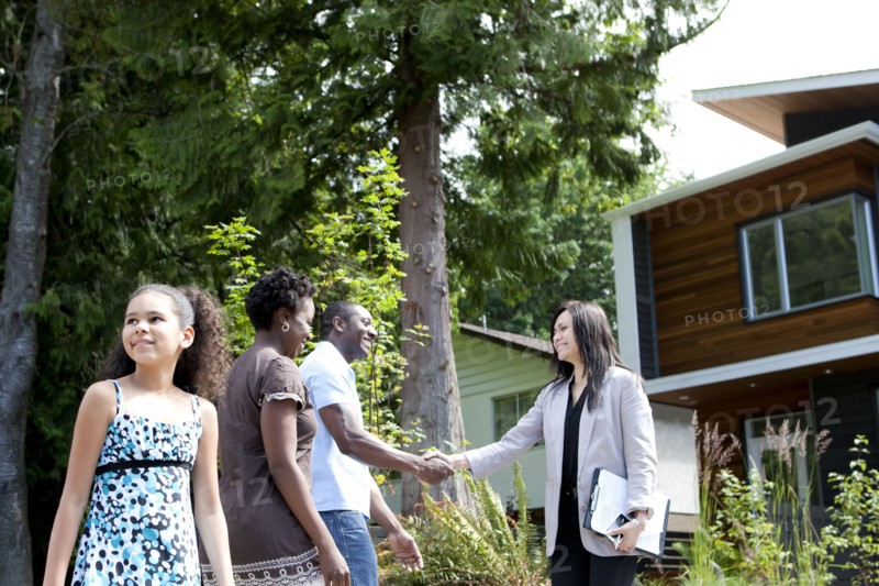 Real estate agent greeting family at house
