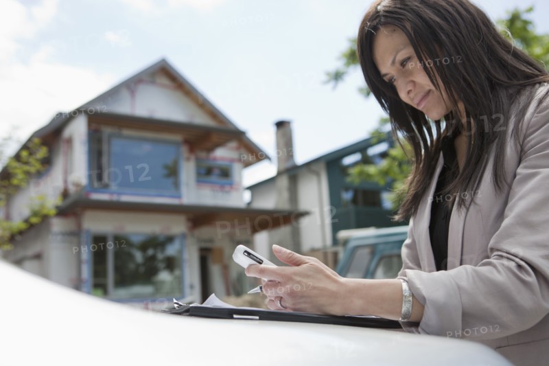 Mixed race real estate agent standing near house under construction