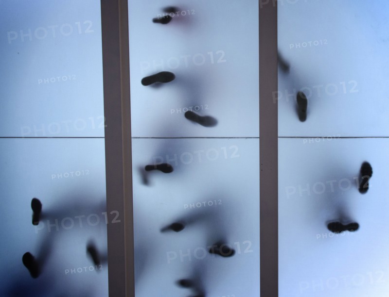 Silhouette of feet standing on glass ceiling