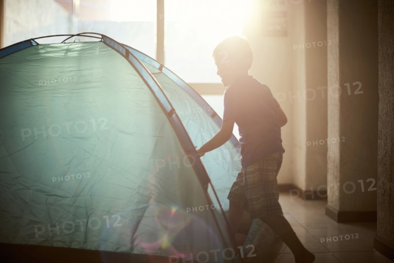 Hispanic boy camping in tent indoors