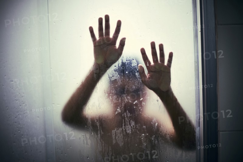 Hands of Hispanic boy leaning on shower door