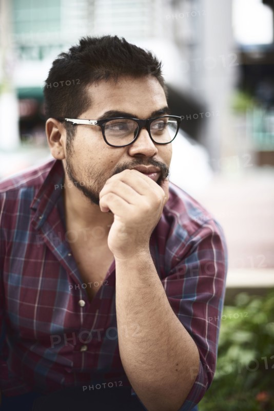 Pensive Hispanic man with hand on chin