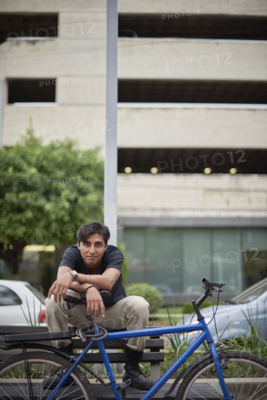 Smiling Hispanic man sitting on bench with bicycle