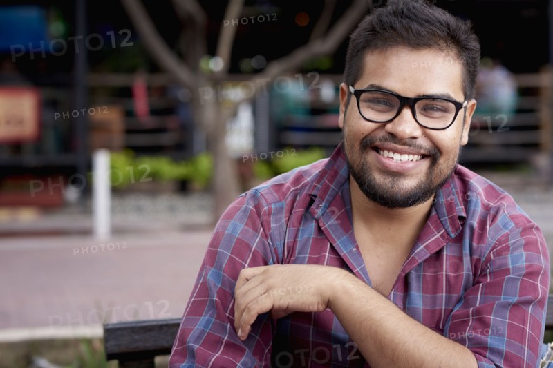 Smiling Hispanic man with beard sitting on bench
